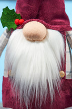 Gnome figure with a beard, red outfit, and holly leaf on a blue background