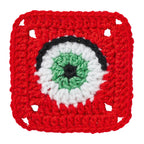 Crocheted square with a central eye design on a white background