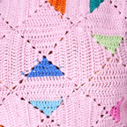Close-up of a pink crocheted blanket with colorful geometric shapes.