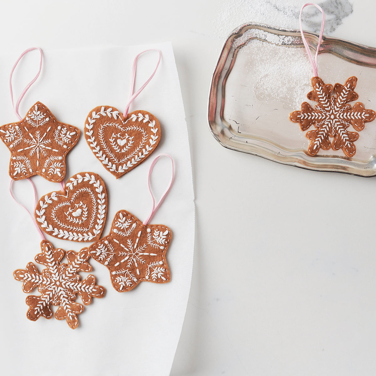Decorative gingerbread ornaments on a white surface with a glass container in the background.