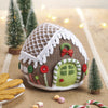Knitted gingerbread house toy with a plate of cookies and candy canes on a festive background.