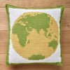 Crocheted pillow with a yellow and green globe design on a wooden surface