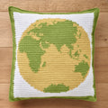 Crocheted pillow with a yellow and green globe design on a wooden surface