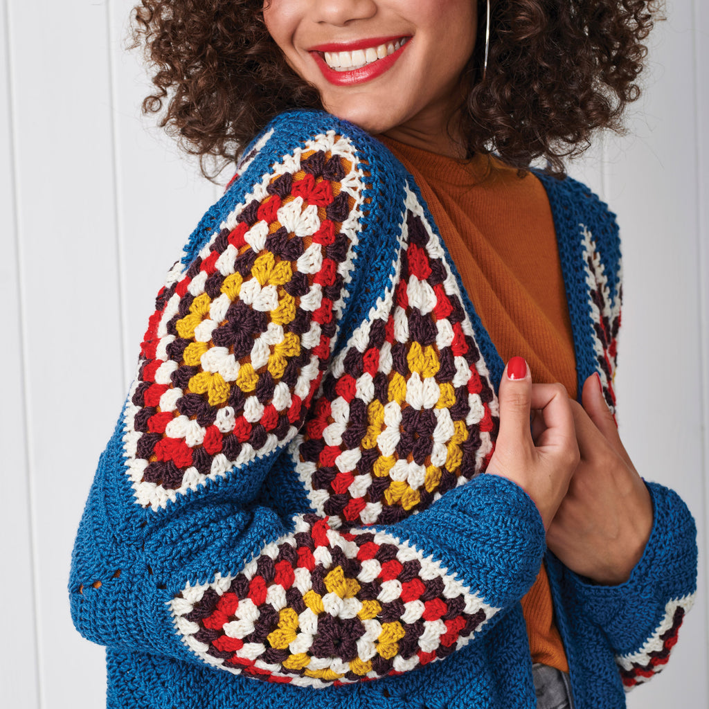 Woman wearing a colorful crocheted cardigan against a white background