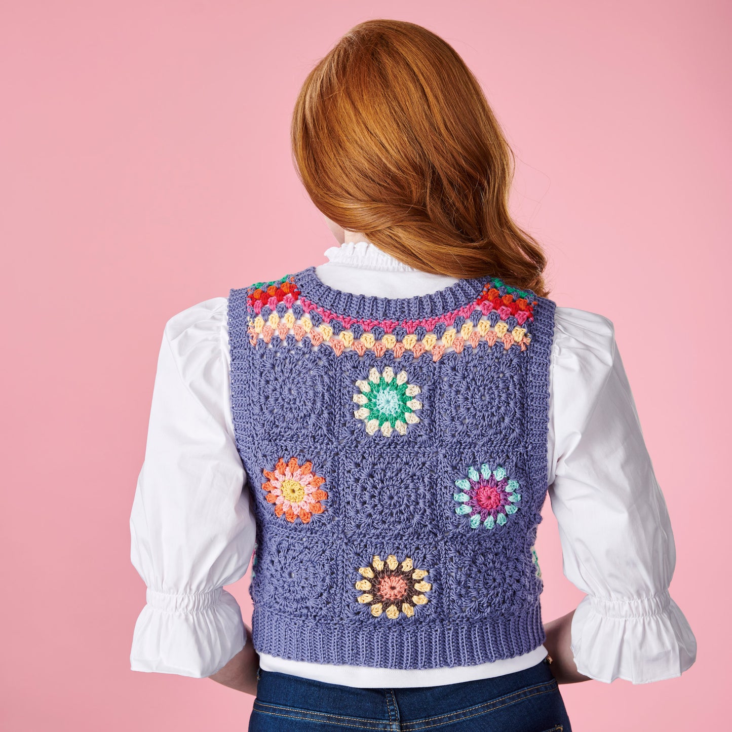 Person wearing a colorful crochet vest on a pink background