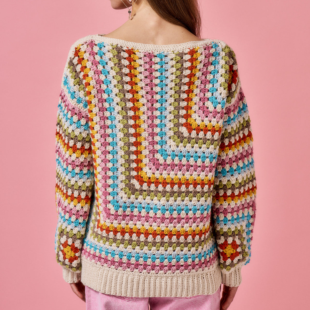 Colorful crochet sweater on a pink background