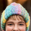 Close-up of a person wearing a colorful crochet hat with a blurred background