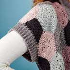 Colorful crocheted shawl with geometric pattern on a blue background