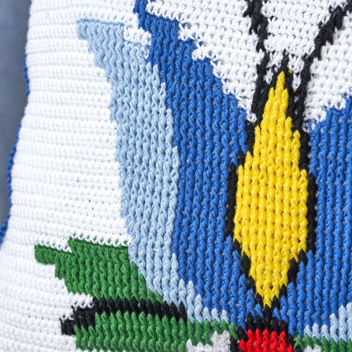 Cross-stitched butterfly with blue wings and a yellow body on white fabric.