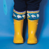 Yellow rain boots with colorful knitted leg warmers on a blue background