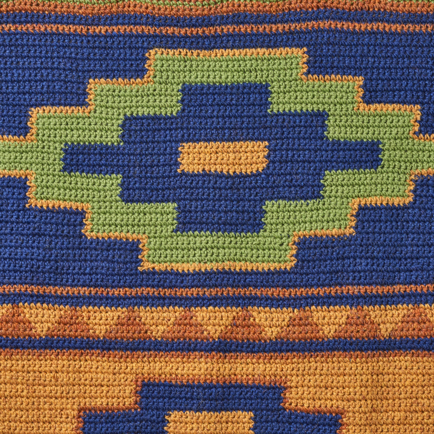Close-up of a woven fabric with geometric pattern in blue, green, and orange.