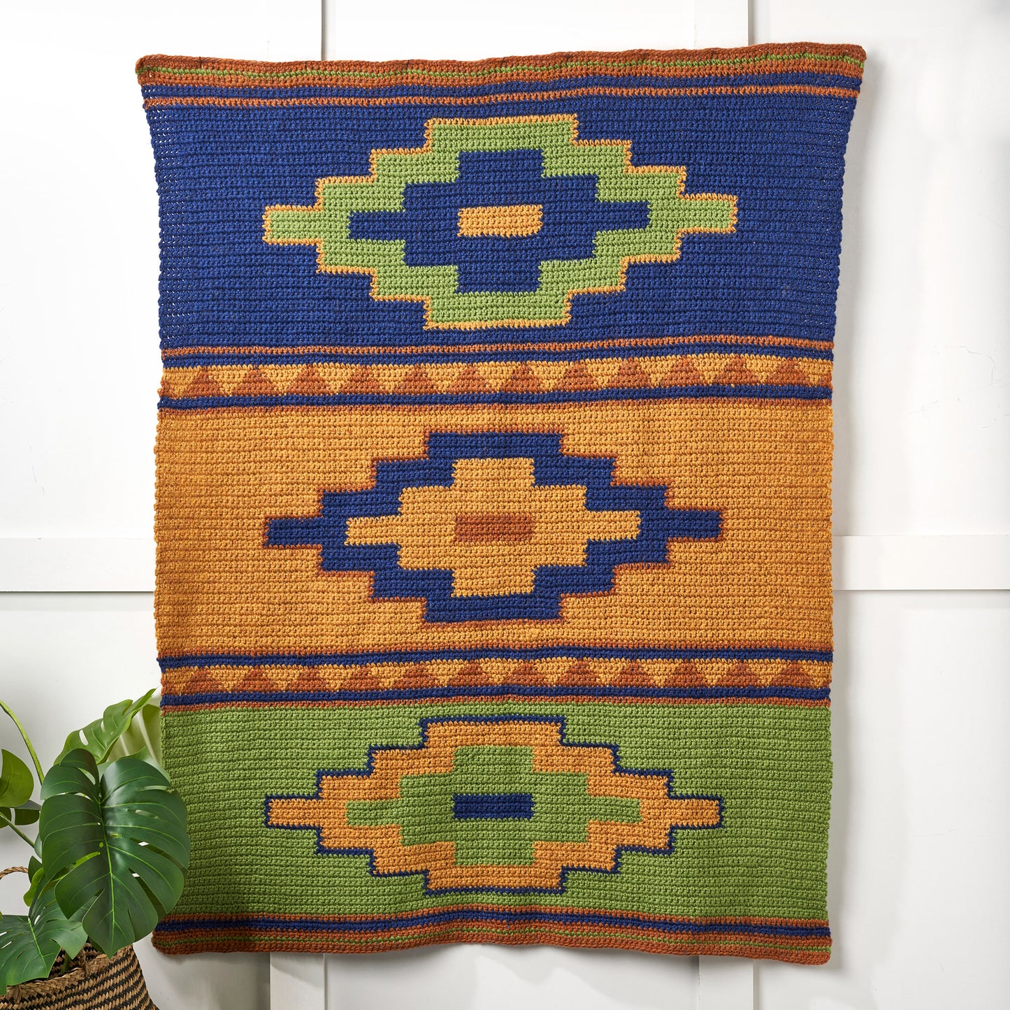 Decorative pillow with geometric wall hanging on a white background