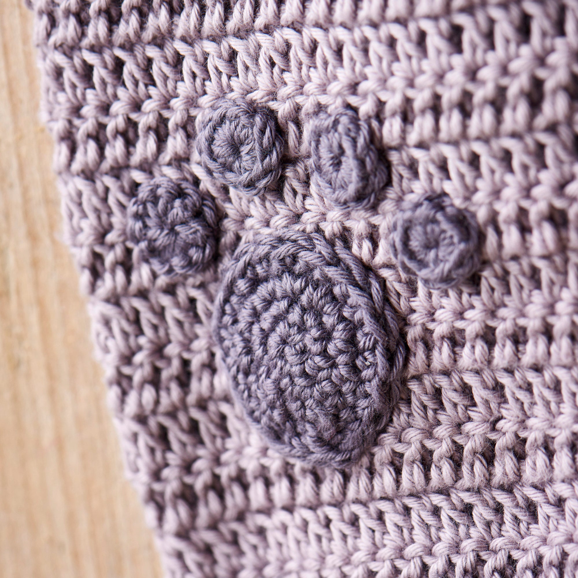 Close-up of a textured fabric with embroidered gray circles on a wooden surface