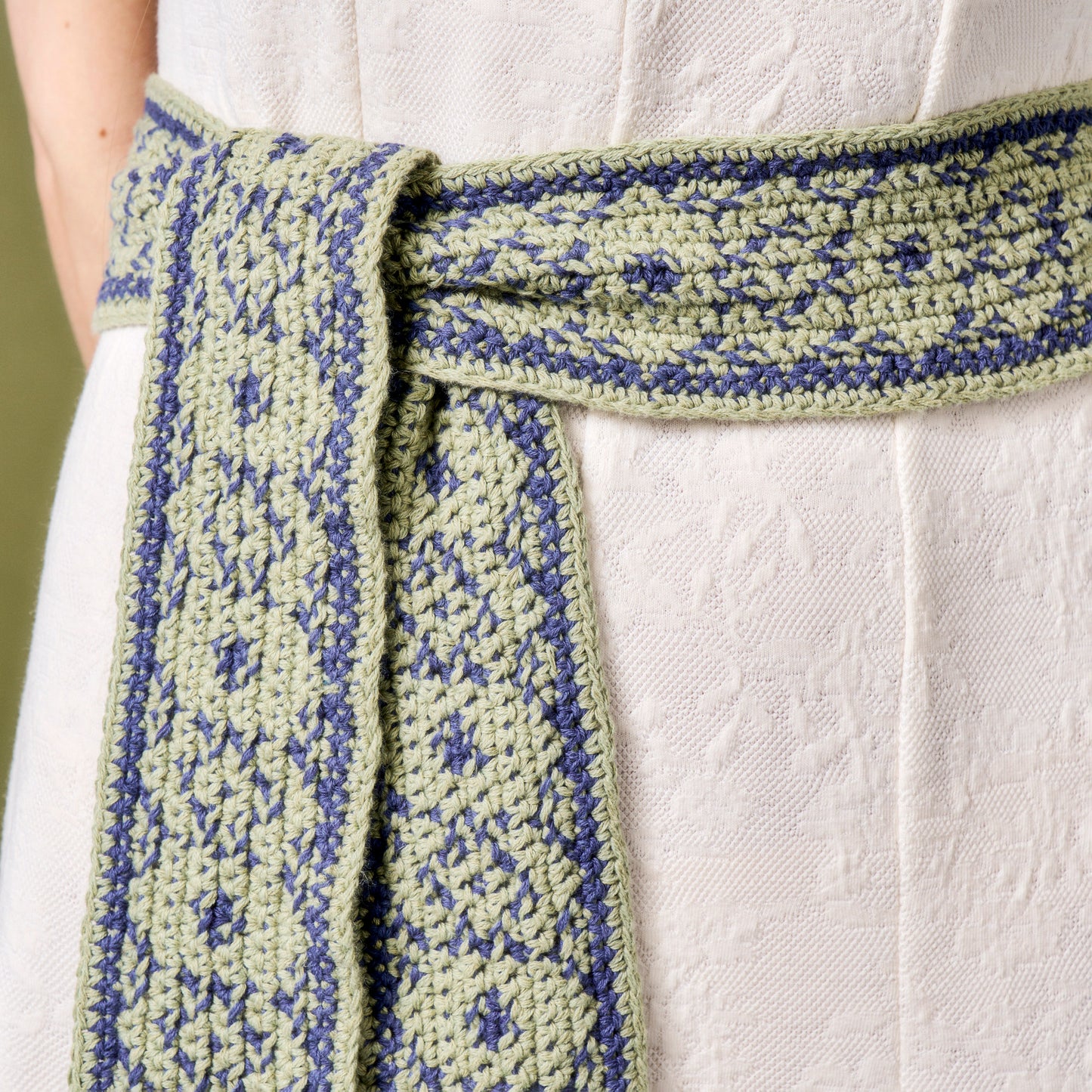 Green and blue patterned belt tied around a white garment