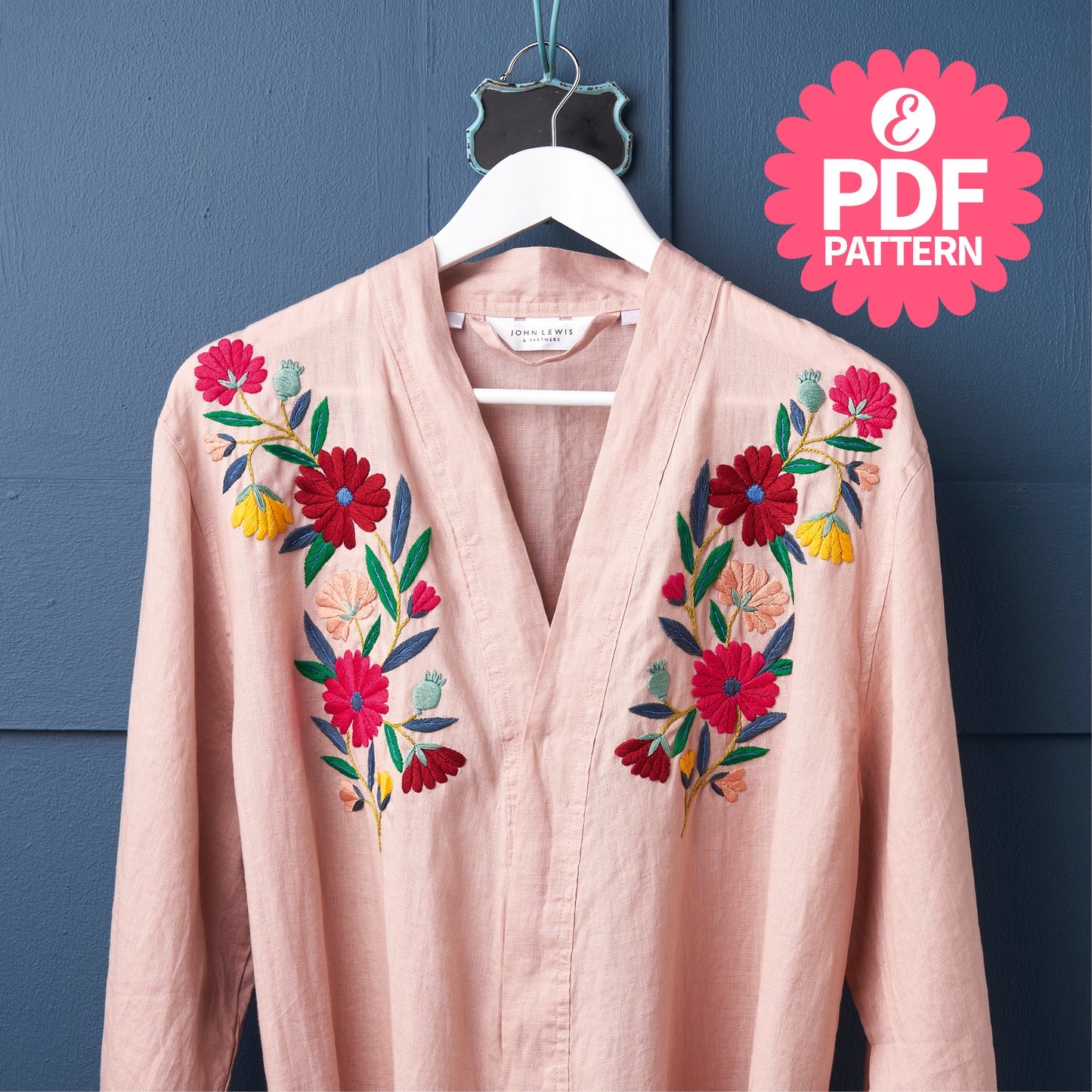 Pink embroidered jacket on a hanger with a blue wall background and PDF pattern logo.
