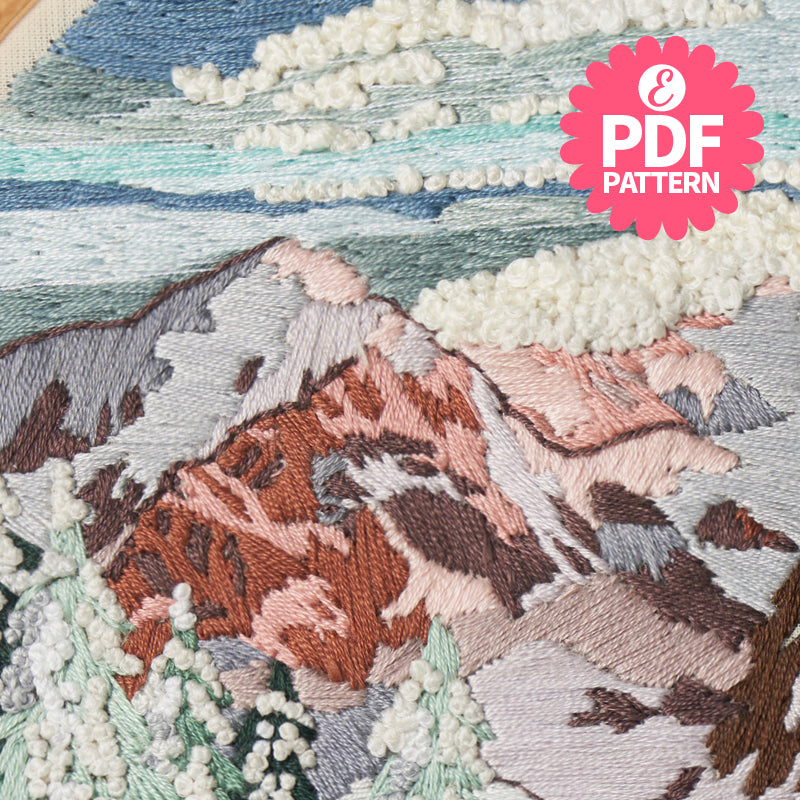 Embroidery of a mountain landscape with a PDF pattern label.