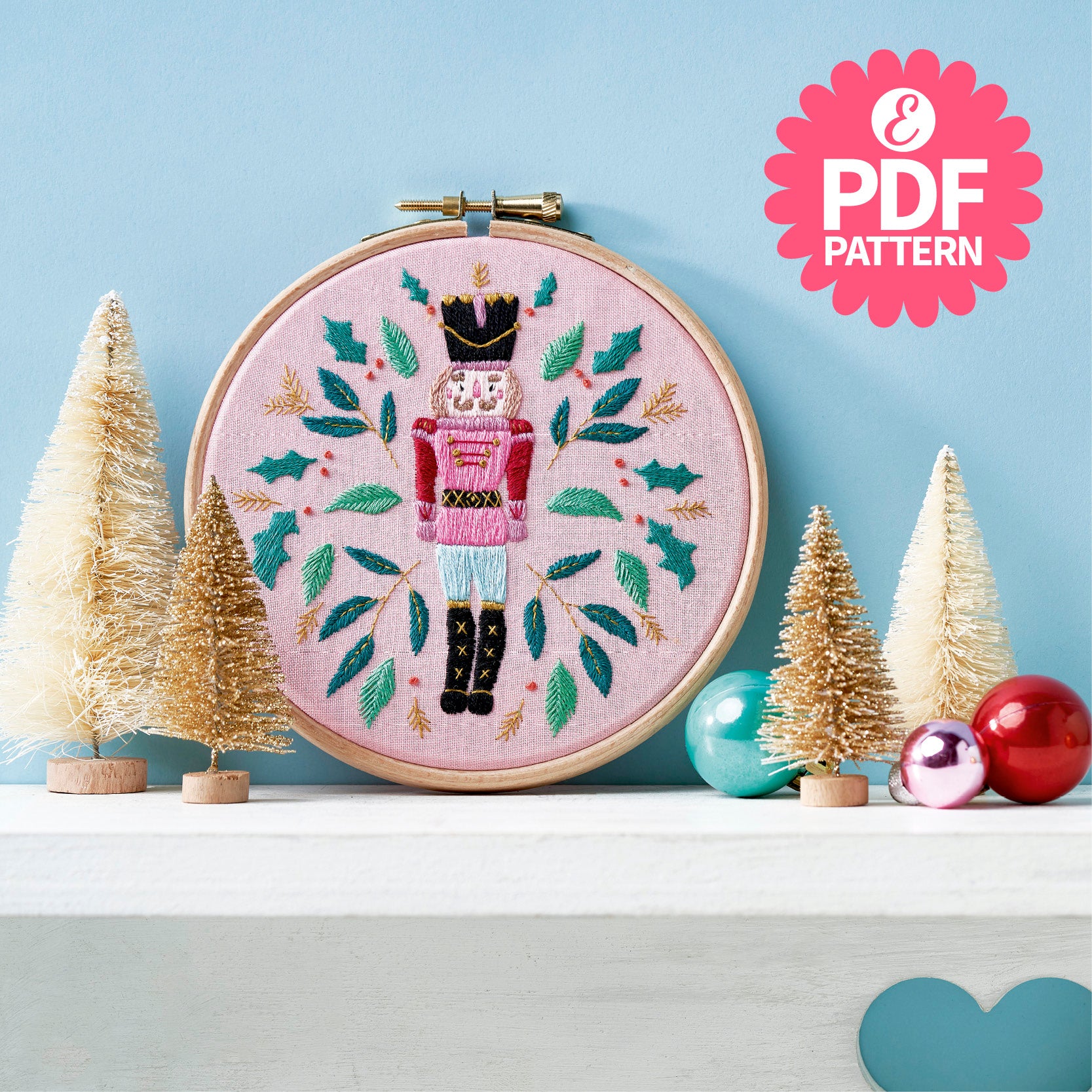 Embroidery hoop with nutcracker design on a shelf with Christmas decor