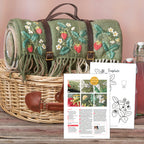 Embroidered roll-up mat with strawberry design in a wicker basket, accompanied by a pattern sheet.