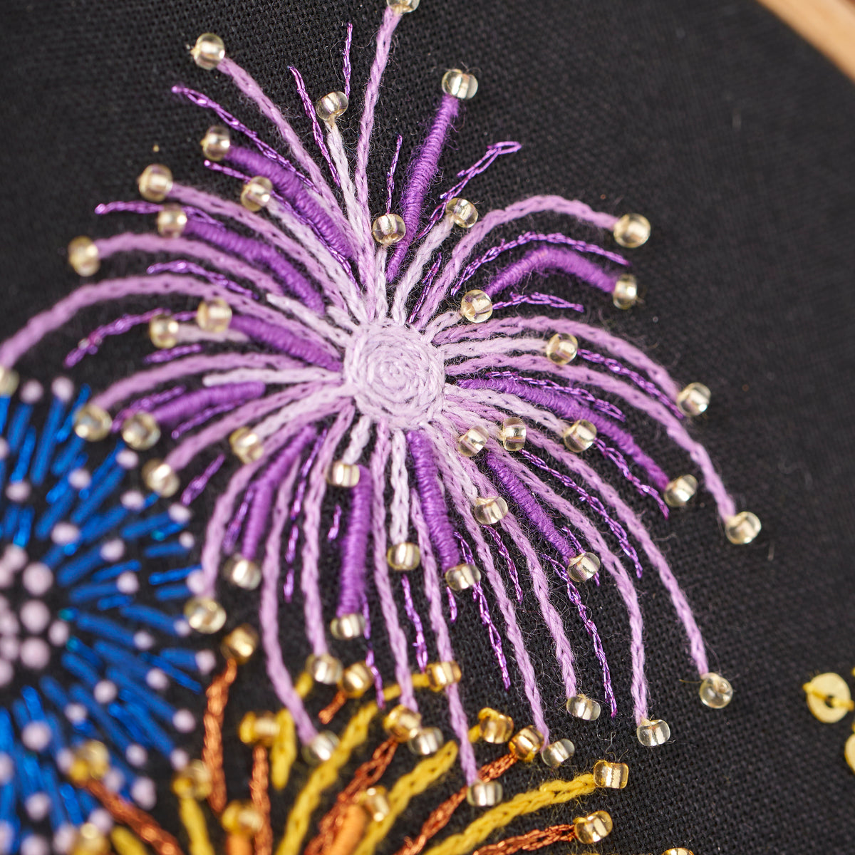 Close-up of embroidered fireworks design on black fabric