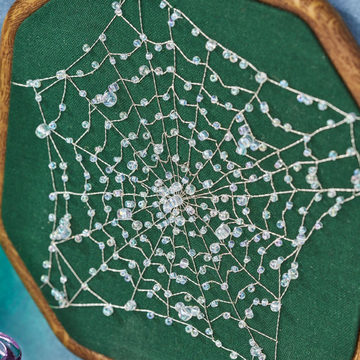 Spiderweb embroidery on a green fabric background