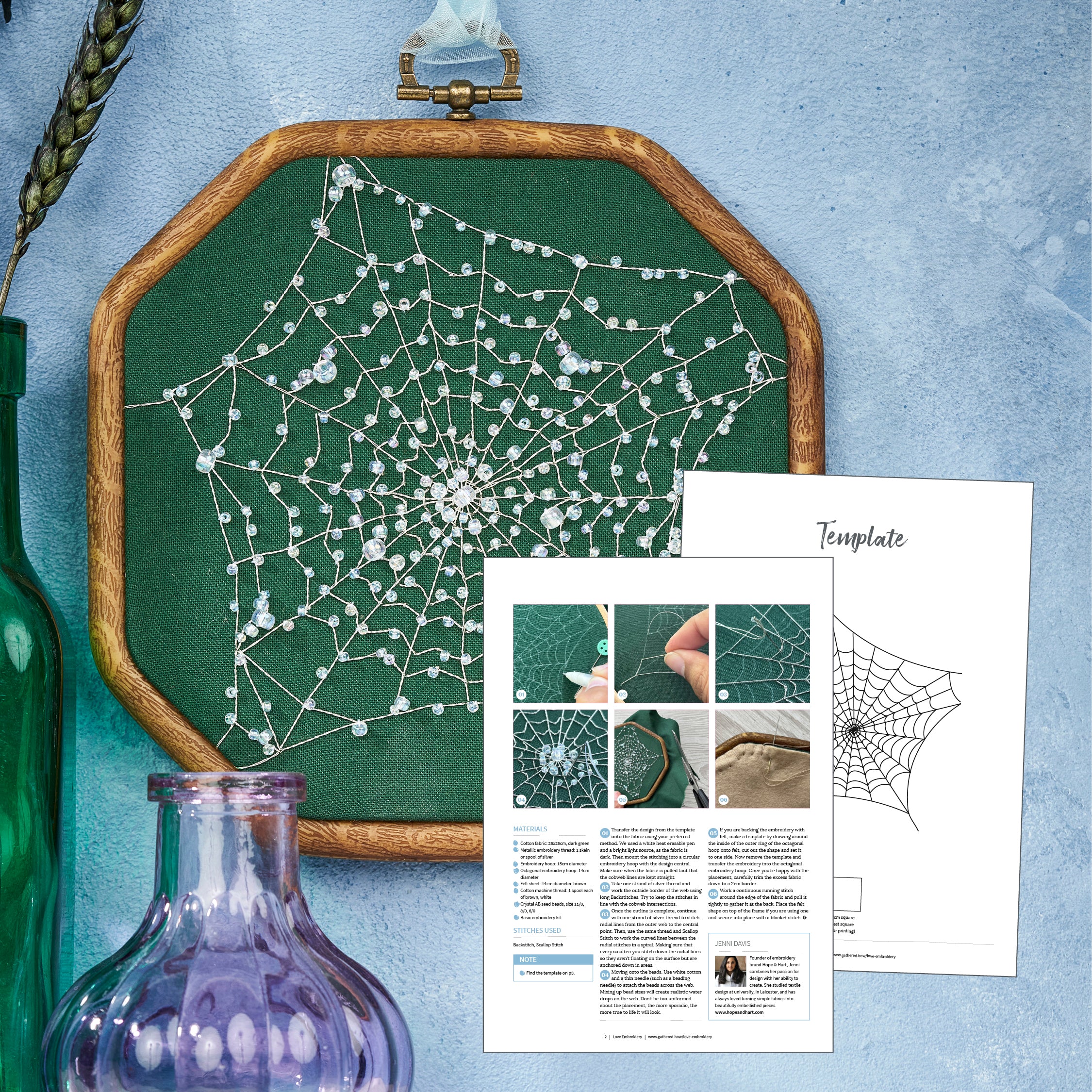 Spiderweb embroidery on green fabric with wooden frame, next to a template sheet on a textured blue background.