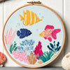 Embroidery hoop with colorful fish and coral design on a light blue background