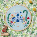 Embroidery hoop with a colorful castle design on a floral background