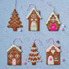 Decorative gingerbread house and tree ornaments on a blue background with sprinkles.