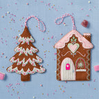 Felt gingerbread house and tree ornaments on a blue background with sprinkles.