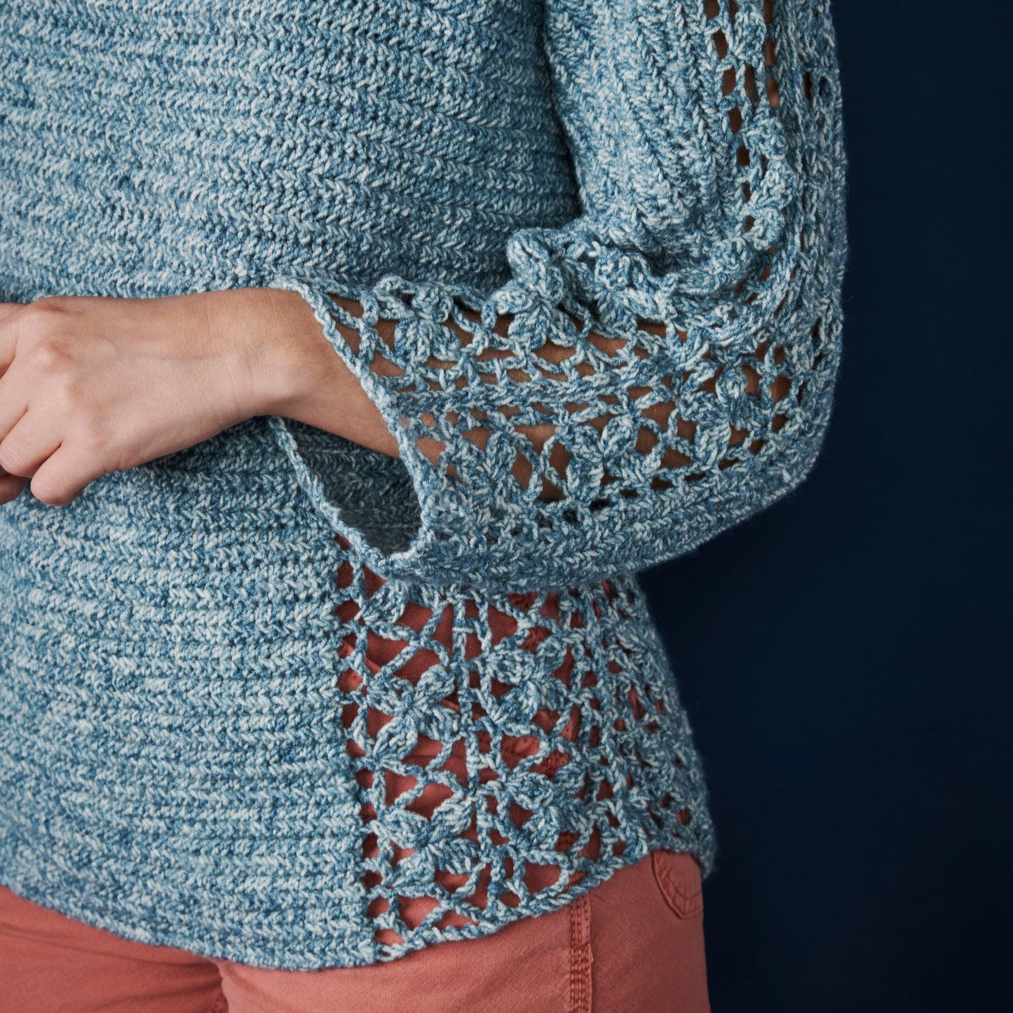 Close-up of a blue knitted garment with intricate lace detailing on a dark background