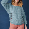 Woman wearing a teal crochet sweater against a blue background