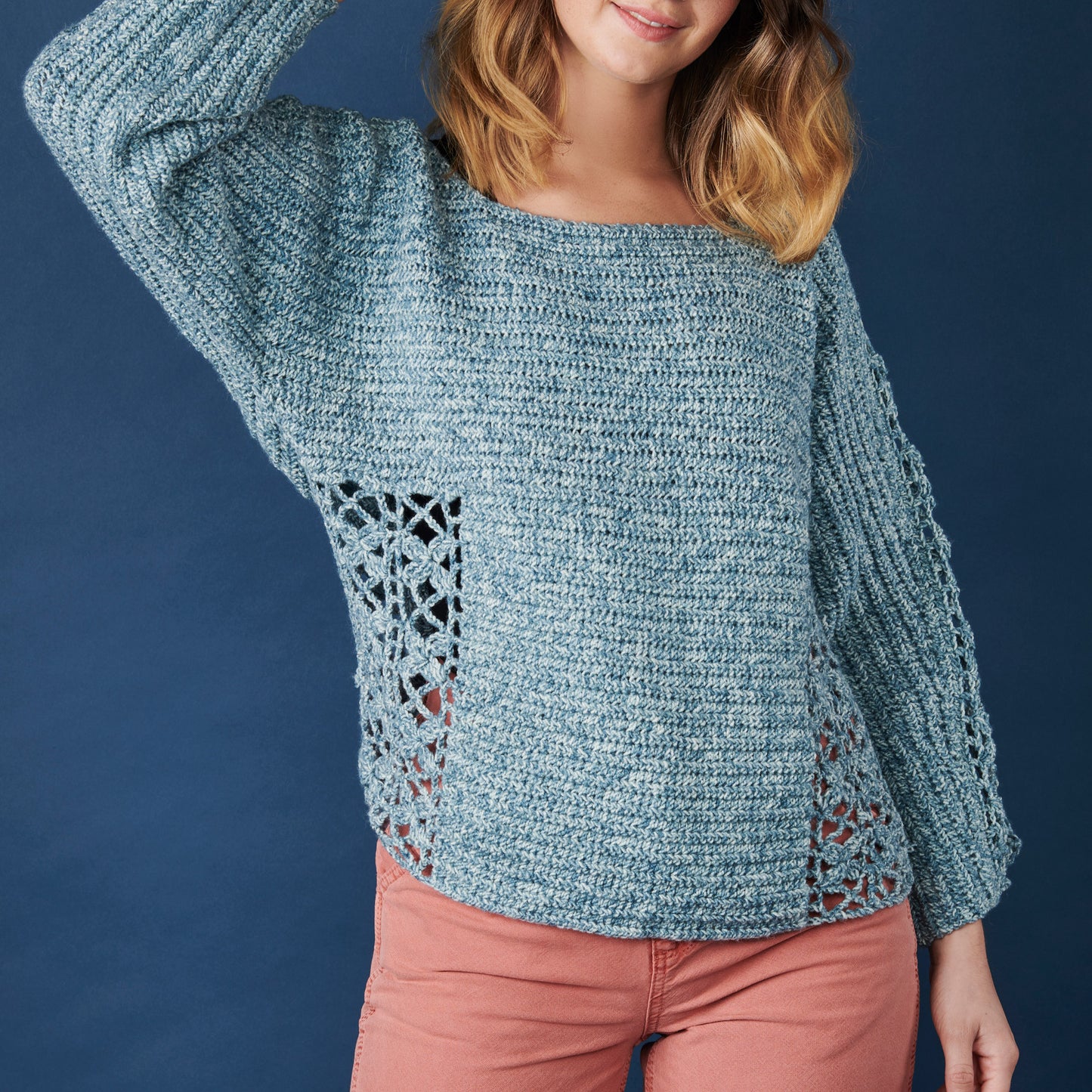 Woman wearing a teal crochet sweater against a blue background