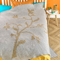 Textured blanket with floral pattern on a bed in a bedroom setting