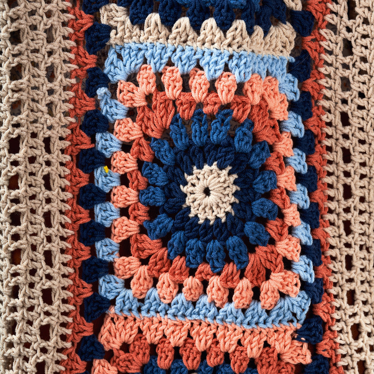 Close-up of a colorful crocheted blanket with a circular pattern.