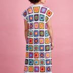 Person wearing a colorful crochet dress against a pink background