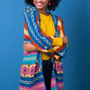 Woman wearing a colorful crocheted shawl against a blue background