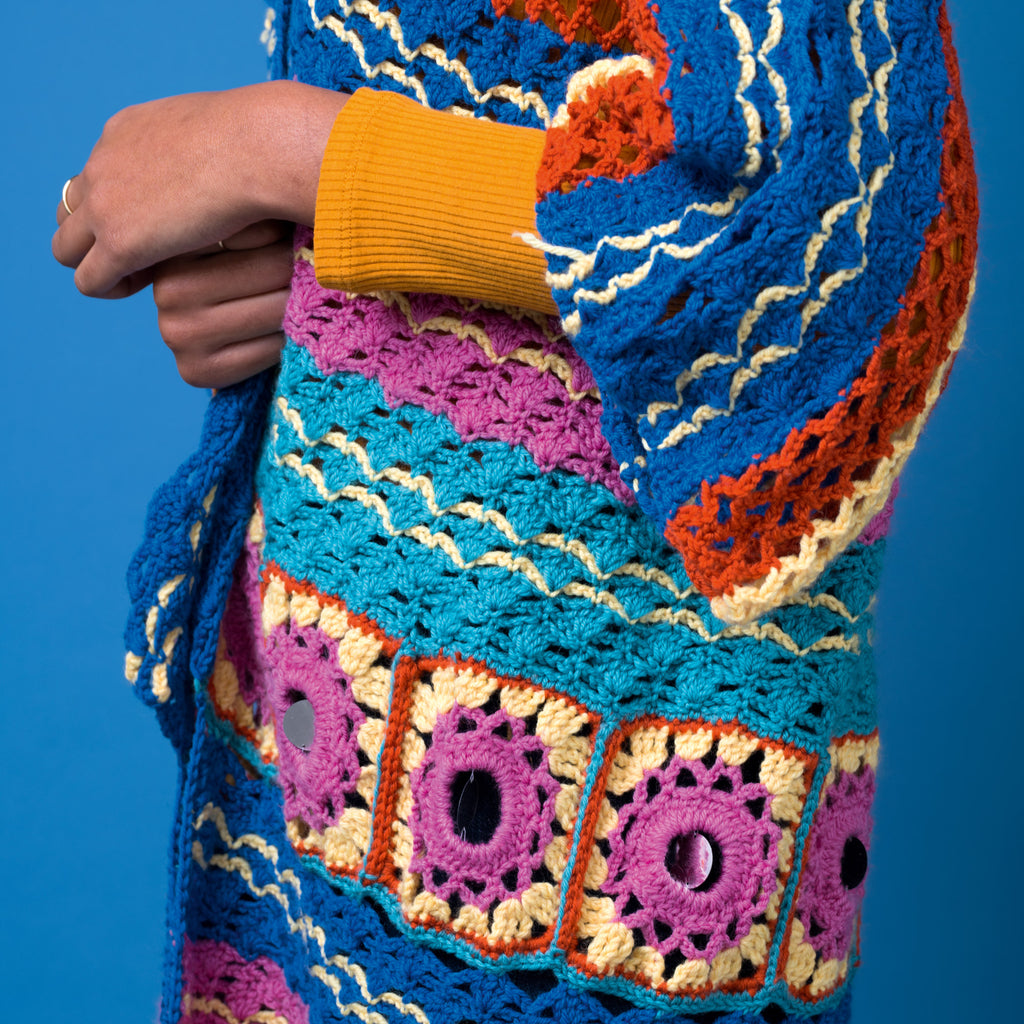 Colorful crocheted sweater with geometric patterns against a blue background