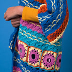 Colorful crocheted sweater with geometric patterns against a blue background
