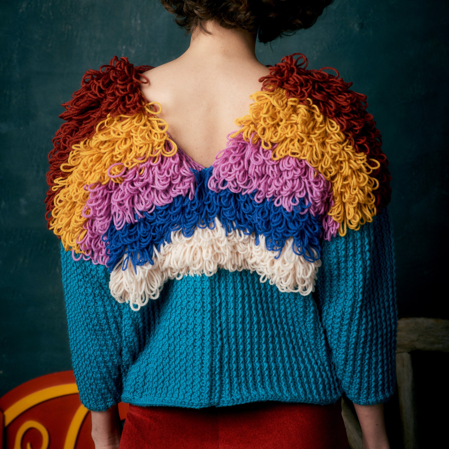 Person wearing a colorful knitted sweater with a dark background