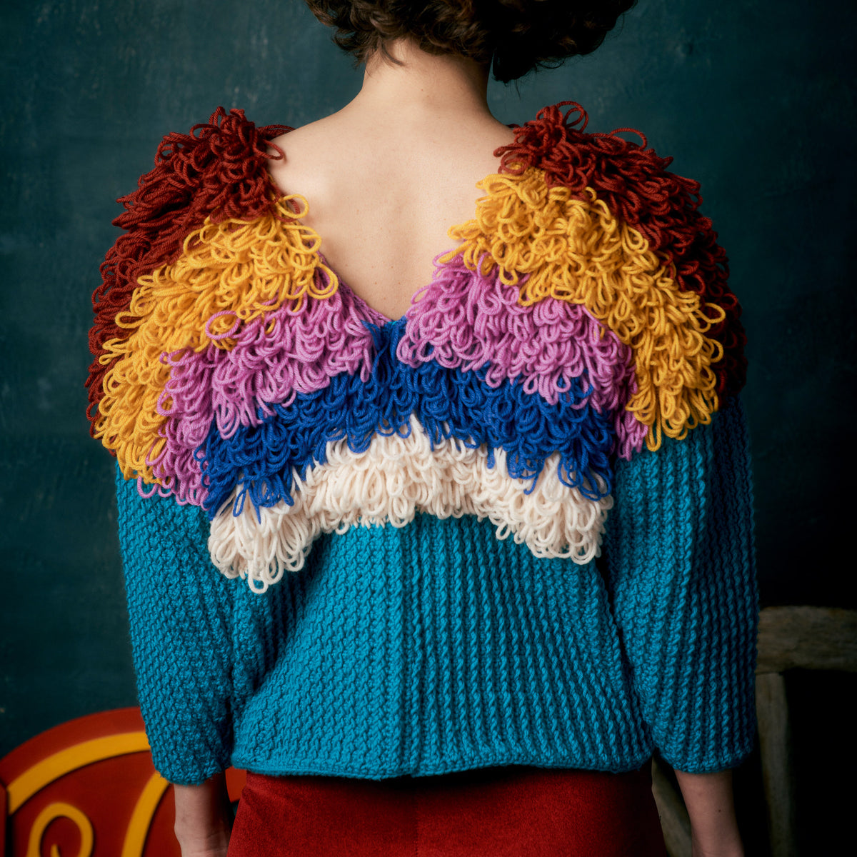 Person wearing a colorful knitted sweater with a dark background
