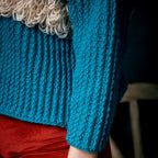 Close-up of a blue knitted garment with a textured pattern.