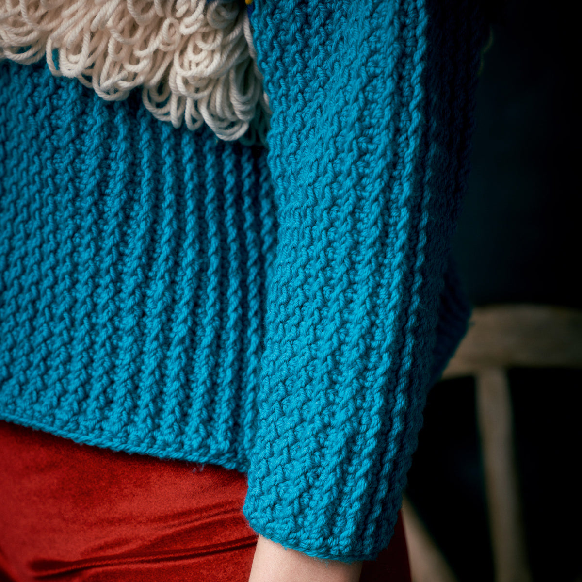 Close-up of a blue knitted garment with a textured pattern.