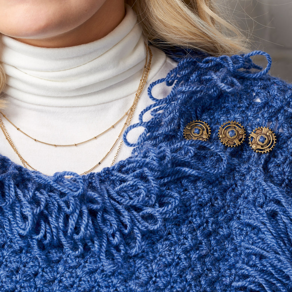 Close-up of a person wearing a blue crochet garment with gold jewelry.