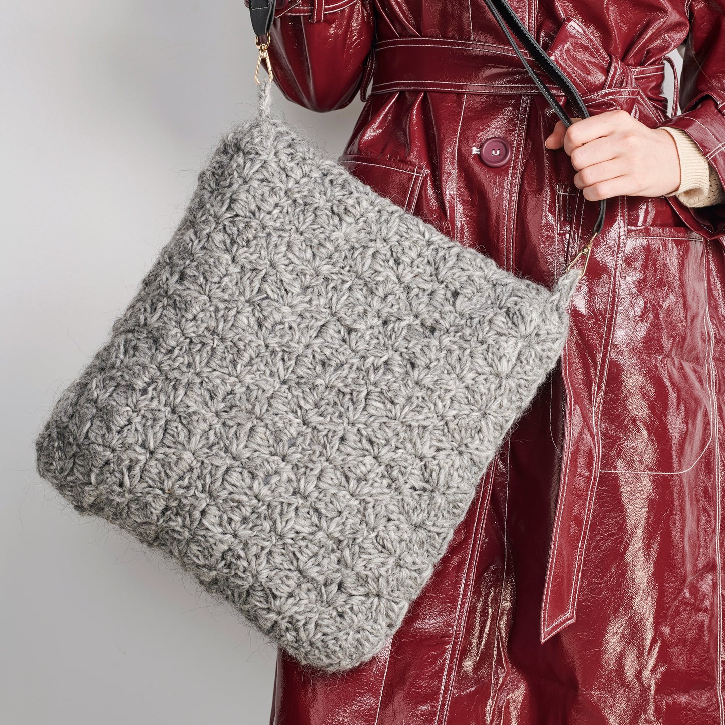 Person holding a textured gray bag against a plain background