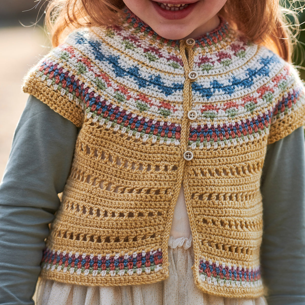 Child wearing a colorful knitted cardigan with a patterned border.