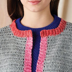 Close-up of a person wearing a colorful knit cardigan with a blue, pink, and gray pattern.