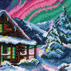 Cross-stitched scene of a snowy cabin with trees and a colorful sky.