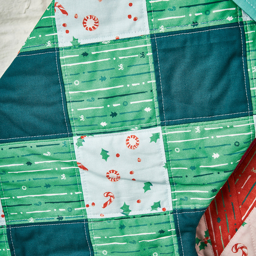 Close-up of a patchwork quilt with green, blue, and white patterns.