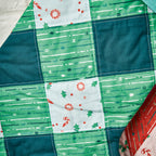 Close-up of a patchwork quilt with green, blue, and white patterns.