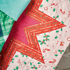 Close-up of a quilt with geometric pattern and Christmas-themed fabric